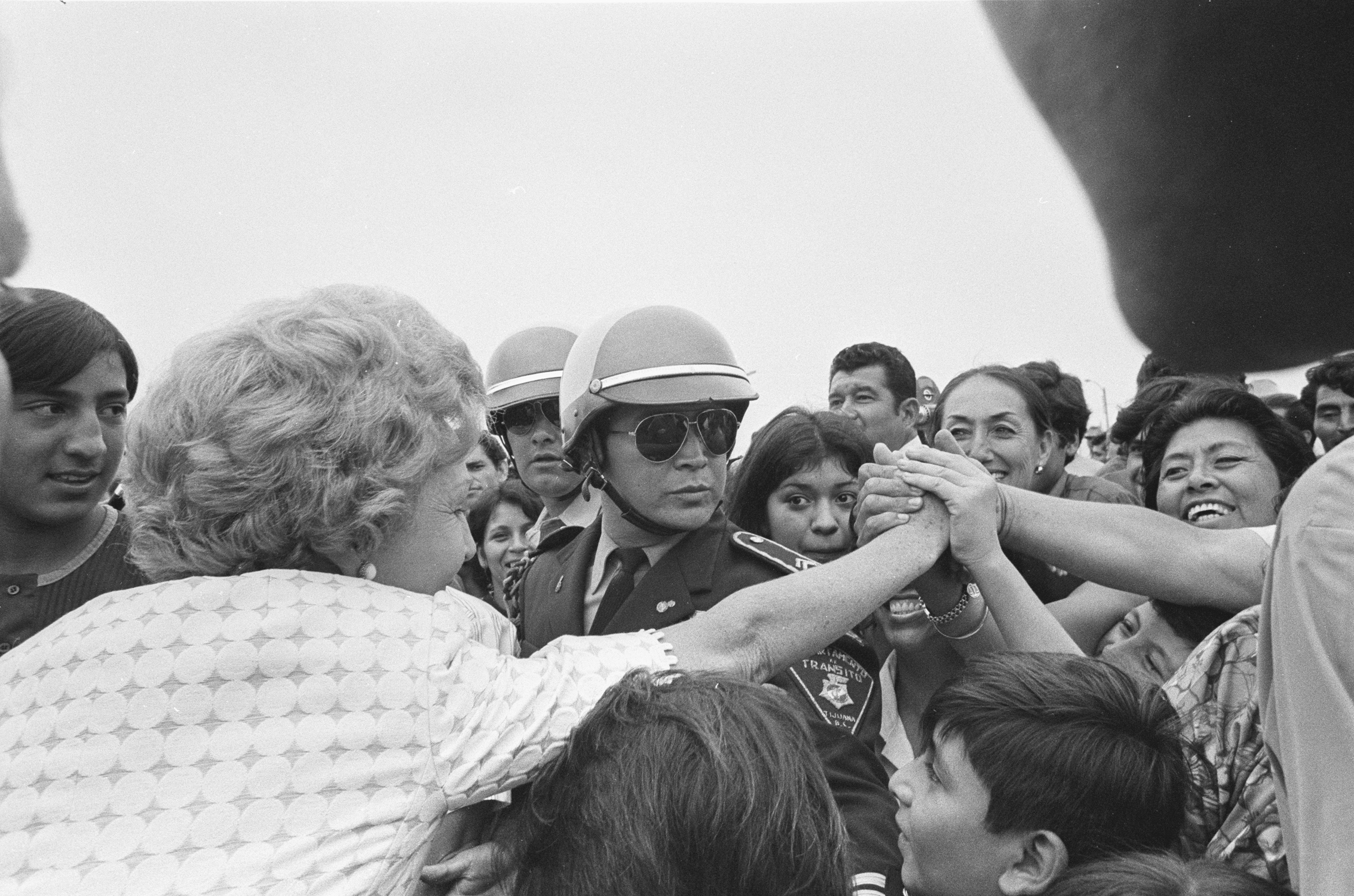 80. Pat Nixon shaking hands with Mexican citizens over the border fence.
