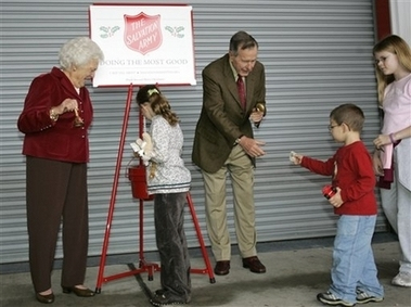 Barbara Bush ringing her Salvation Army Christmas bell as George Bush accepts contributions for the charitable organization