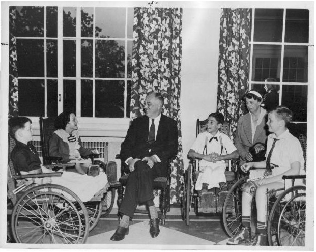 FDR with young polio patients at Warm Springs, Georgia rehabilitative center. First Lady Eleanor Roosevelt looks on, at right.