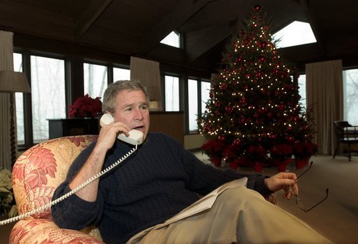 President George W. Bush talks during Christmas Eve telephone calls to members of the Armed Forces at Camp David, Wednesday, Dec. 24, 2003 .