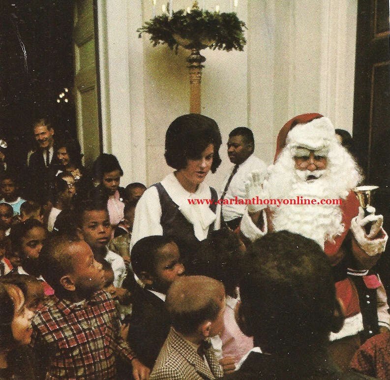 Luci Johnson and Santa Claus leading local children into the East Room for her 1965 holiday party.