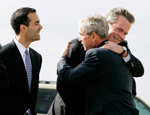 George P. Bush looks on as his father and uncle, brothers and First Sons, Florida Governor Jeb and President George W. embrace.