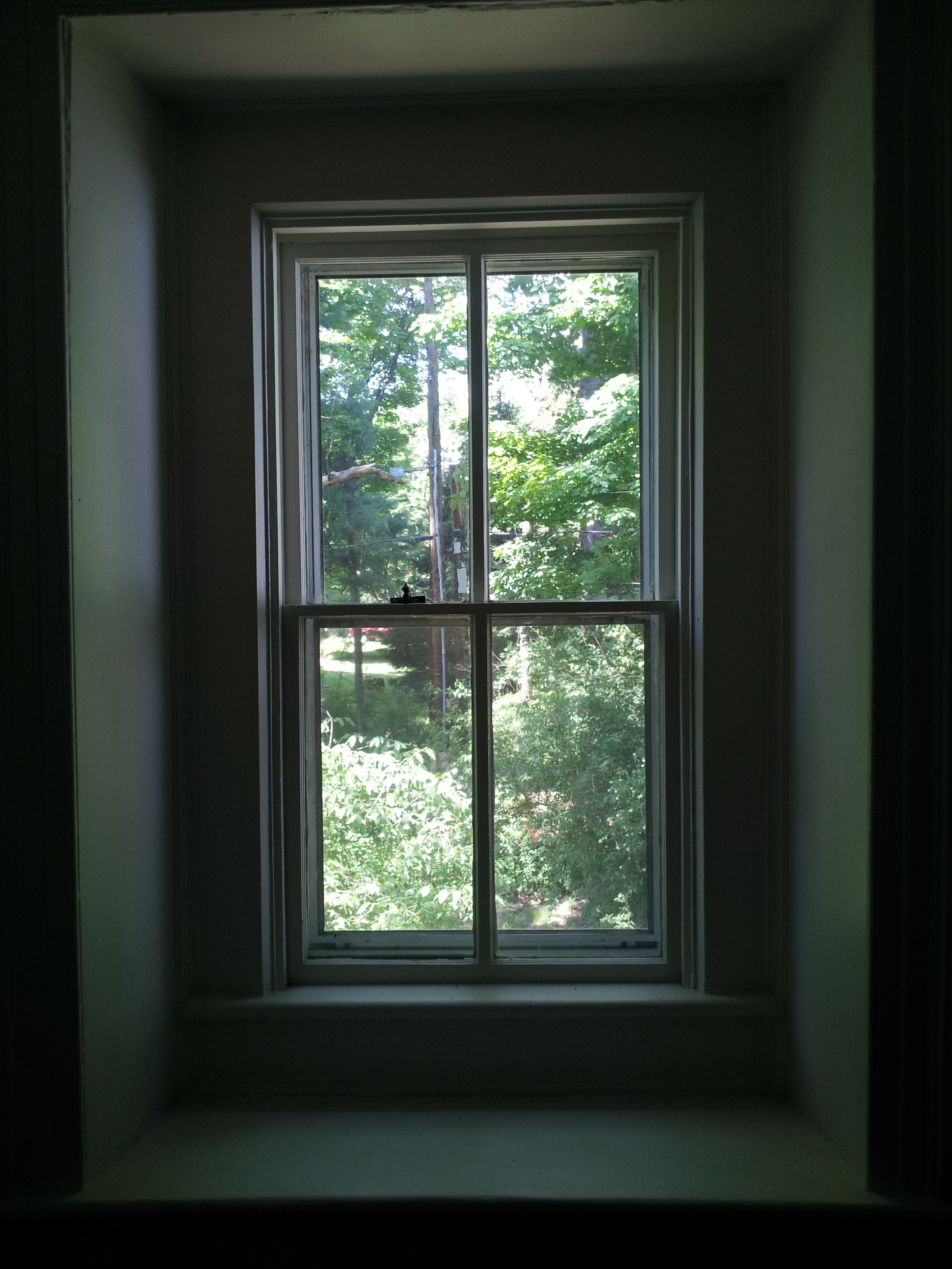 A window in an 18th Century Dutch stone cottage in Woodstock, New York looking out on the green of the surrounding forest.