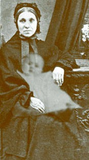 A Victorian mother with her dead child's image superimposed on her lap as a ghost.