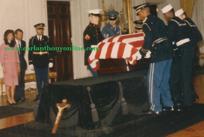 Jacqueline Kennedy with brother-in-law Robert F. Kennedy watch as the flag-draped coffin of President Kennedy is placed on a bier in the White House East Room.